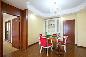 Una habitación con mesa de billar, sillas rojas y blancas, una estantería y una puerta de madera.