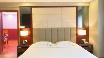 A hotel room with a large bed, two bedside tables with lamps, a mirror, and a wooden chair.