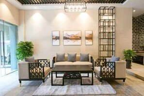 Una sala de estar moderna con un sofá, dos sillones, una mesa de centro y un separador decorativo.