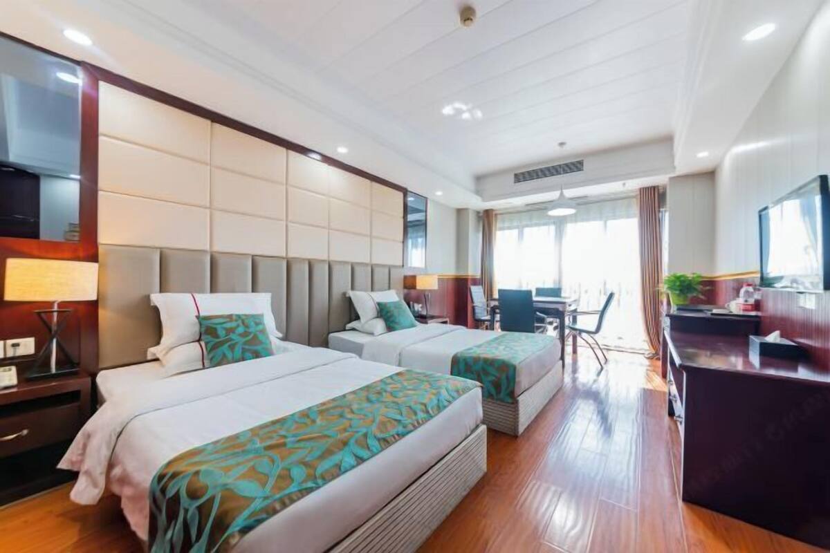 Une chambre d’hôtel avec deux lits, un bureau et une chaise.