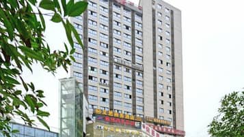 A high-rise building with multiple floors, large windows, and a prominent entrance with signage.