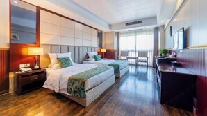 Habitación de hotel con una cama grande, dos mesitas de noche, un escritorio y un balcón con vistas.