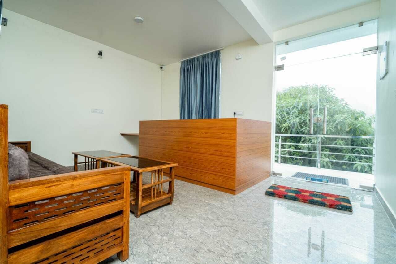 Una habitación moderna con sofá de madera, una mesita, una recepción y un balcón con vistas a zonas verdes.
