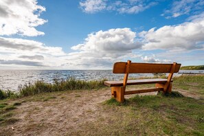 A wooden bench by a body of water with a clear sky.