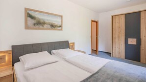 A bedroom with a bed, a nightstand, a bedside table, a wooden door, and a painting on the wall. - Cozy vacation apartment in the countryside, with sauna and garden (Garz)