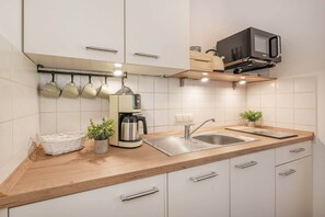Una cocina moderna con un lavamanos de acero inoxidable, una cafetera y un microondas en un estante superior.