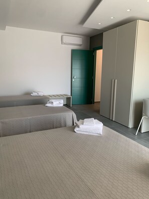 A modern hotel room with two beds, a wardrobe, and a green door. - B&B The Princess (Montecorvino Pugliano)