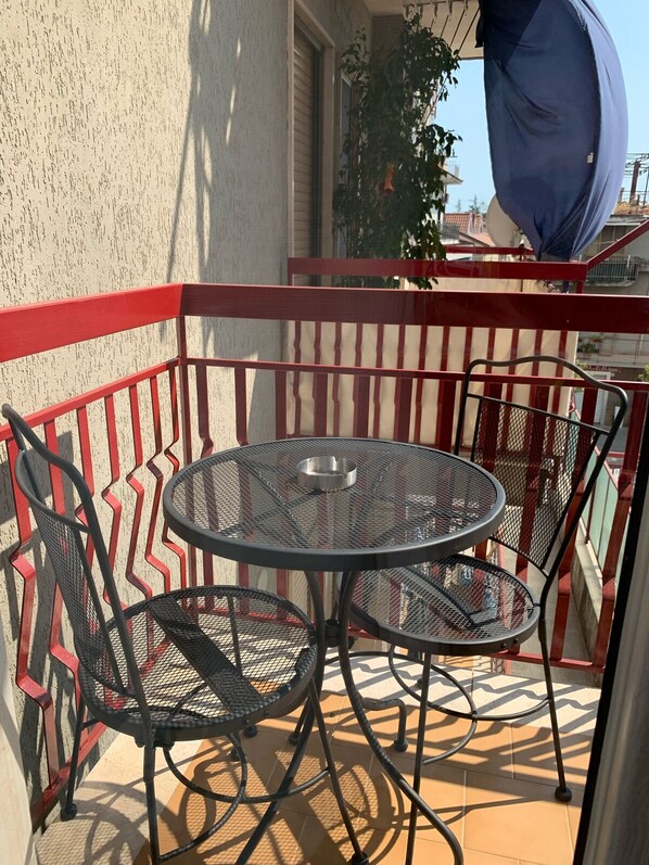 A balcony with a round metal table and two chairs, a red railing, and a view of buildings in the background. - B&B The Princess (Montecorvino Pugliano)