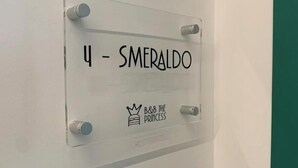 Selkeä kyltti, jossa lukee teksti ”4 – SMERALDO” ja on näkyvissä ”B&B THE PRINCESS” -brändin logo.