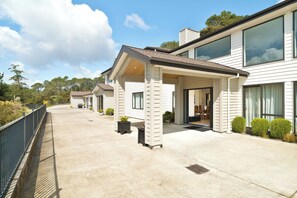 A modern two-story house with a covered patio area, large windows, and a well-maintained garden.