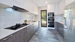 Una cucina moderna con piano cottura a gas, forno integrato e frigorifero in acciaio inossidabile.