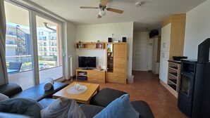 Una sala de estar moderna con un sofá, una mesa de centro, un televisor y un ventilador de techo.