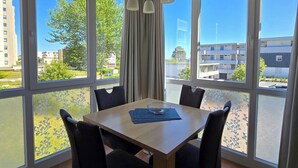 Un comedor moderno con una mesa y sillas, ventanas amplias y vistas de la ciudad.