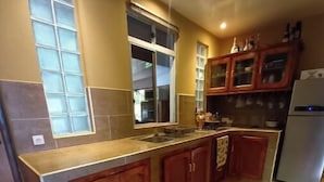 Una cocina con armarios de madera, una encimera, un lavabo y un refrigerador.