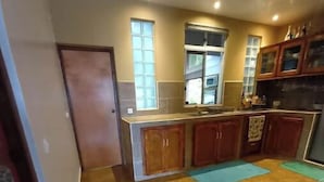 Una cocina con piso de baldosas, armarios de madera y un ventanal.
