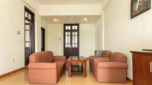 A spacious living area with two sofas and a coffee table, a wooden cabinet, and a door with glass panels. - Cua Dai Beach Hotel (Da Nang)