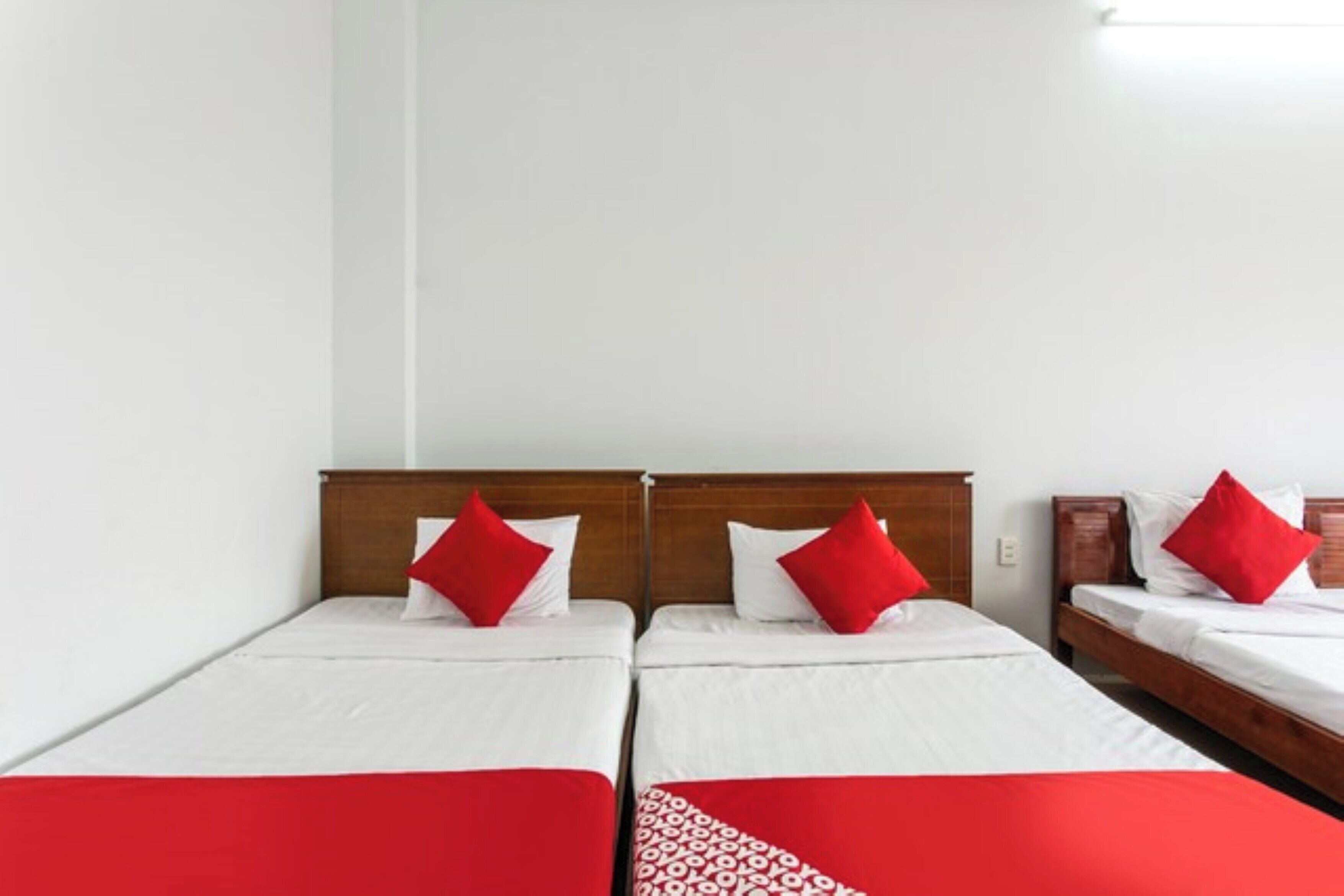Una habitación de hotel con dos camas individuales, cada una con cabecero de madera y ropa de cama blanca.
