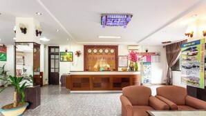 A hotel lobby with a reception desk, seating area, and a clock on the wall. - Cua Dai Beach Hotel (Da Nang)