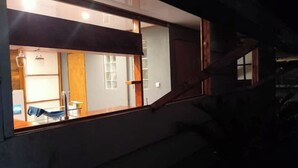 Une pièce dotée d’une grande fenêtre, d’un escalier en bois et donnant sur un couloir avec une porte et un luminaire.