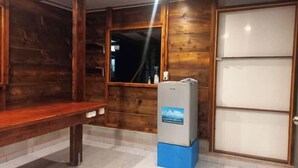 Un intérieur en bois avec un banc, un réfrigérateur et une porte.