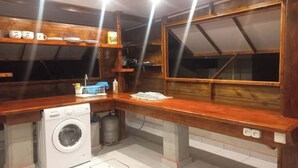 Une cuisine compacte équipée d’un lave-linge, dotée de plans de travail en bois et d’une grande fenêtre.