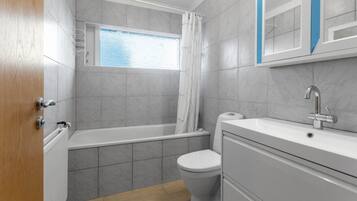 Une salle de bain avec une baignoire, des toilettes et une fenêtre.