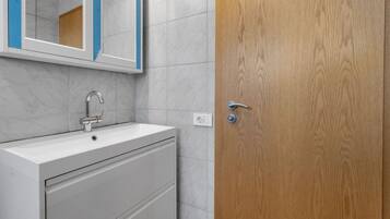 A bathroom with a white sink, a mirror, and a wooden door.