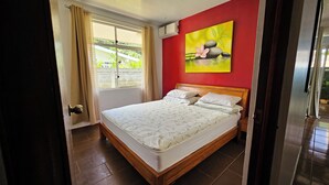 Ein Schlafzimmer mit einem hölzernen Bett, einer roten Wand und einem Fenster mit Vorhängen.