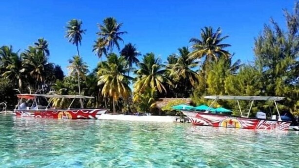 Ein klares, tropisches Schwimmbecken mit Booten und Palmen im Hintergrund.
