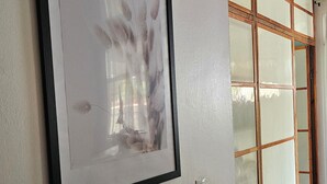 Ein Flur mit einem gerahmten Kunstwerk an der Wand und einer Glastür mit Holzrahmen.