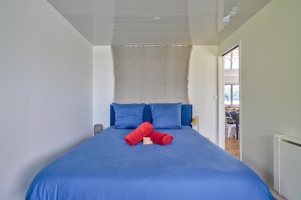 A bedroom with a large bed, blue bedding, and two red towels.