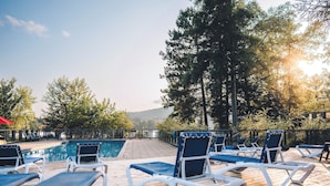 Un espace aménagé au bord de la piscine, avec des chaises longues et une terrasse en bois.