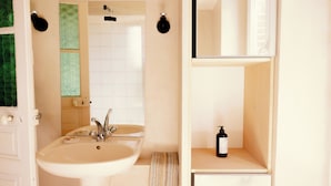 Une salle de bain avec un double lavabo, un miroir et une étagère sur laquelle se trouve une bouteille.