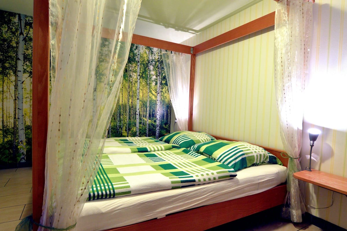 A bed with a canopy, striped bedding, and a nightstand with a lamp.