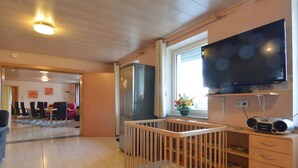 Ein Wohnzimmer mit einem hölzernen Babybett, einem Fernseher und einem Radio.