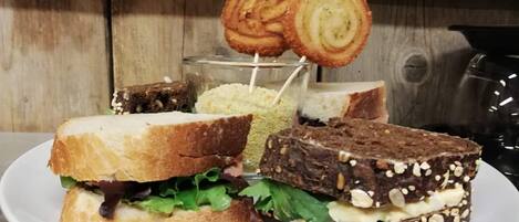 A sandwich with a slice of bread on a toothpick, a piece of cake, and a dessert with nuts on a plate.