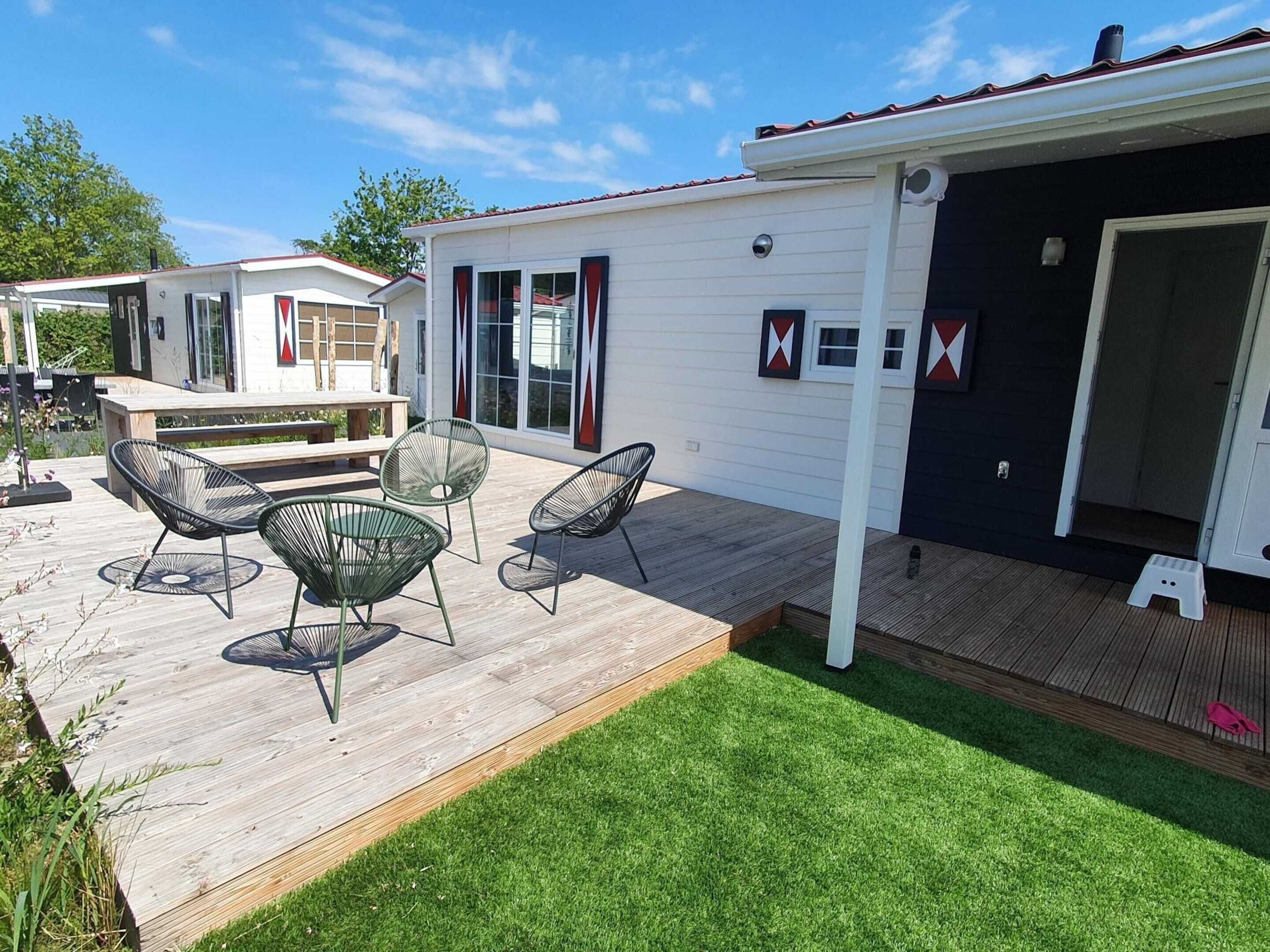 A mobile home with a deck, outdoor seating, and a small garden area.