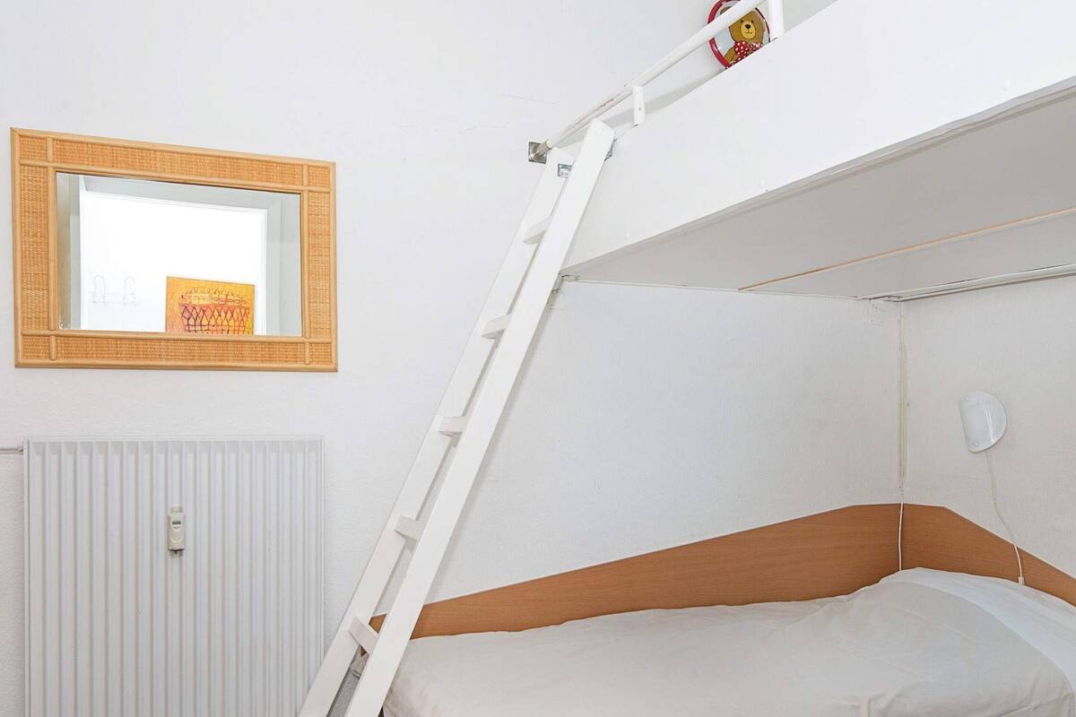 A bunk bed with a ladder, a mirror, and a radiator in a room.