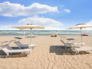 A beach with sun loungers and umbrellas, a lifeguard tower, and the ocean in the background. - Apartment in Northern Zone of Riccione, 150 Meters From the sea (Riccione)