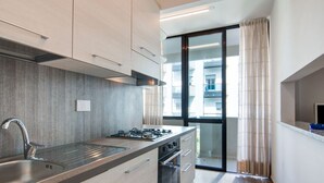 Et moderne køkken med en stålvask, gasblus og en skydedør til en balkon.