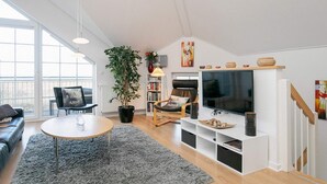 Un salon moderne comprenant un canapé, une table basse, un téléviseur et une bibliothèque.