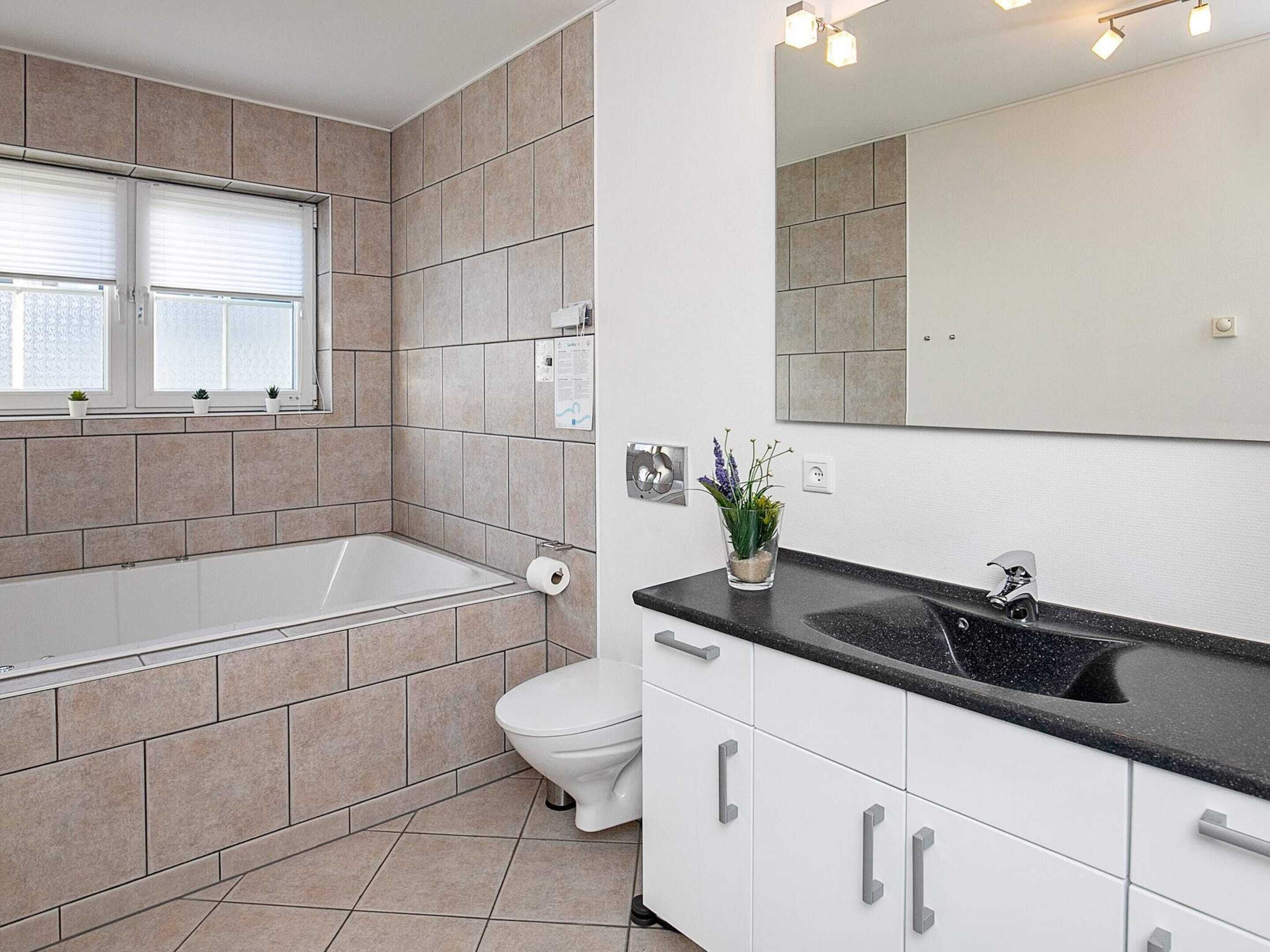 A modern bathroom with a bathtub, toilet, and sink.