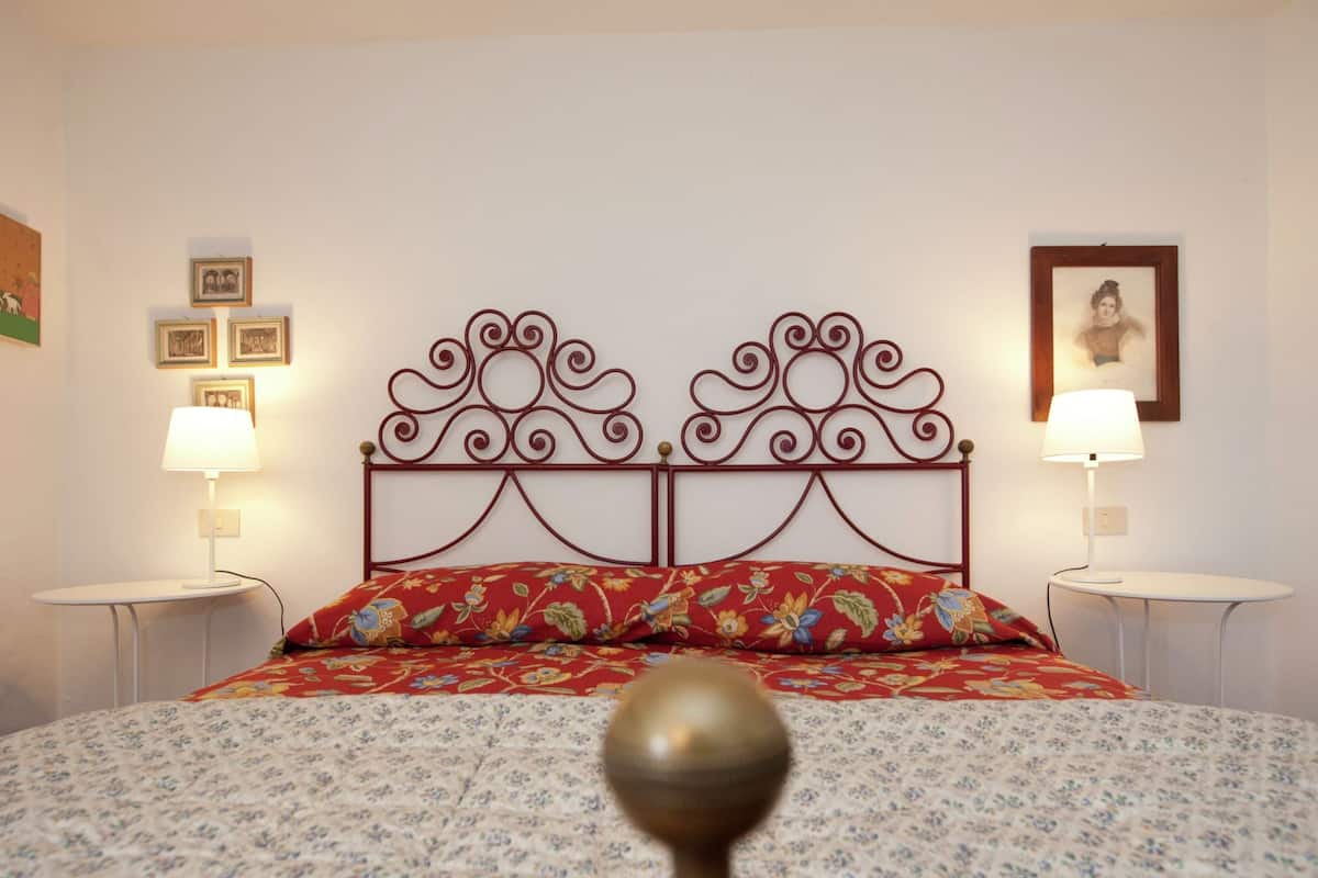 A bed with a floral-patterned bedspread, a decorative metal headboard, and two bedside lamps.