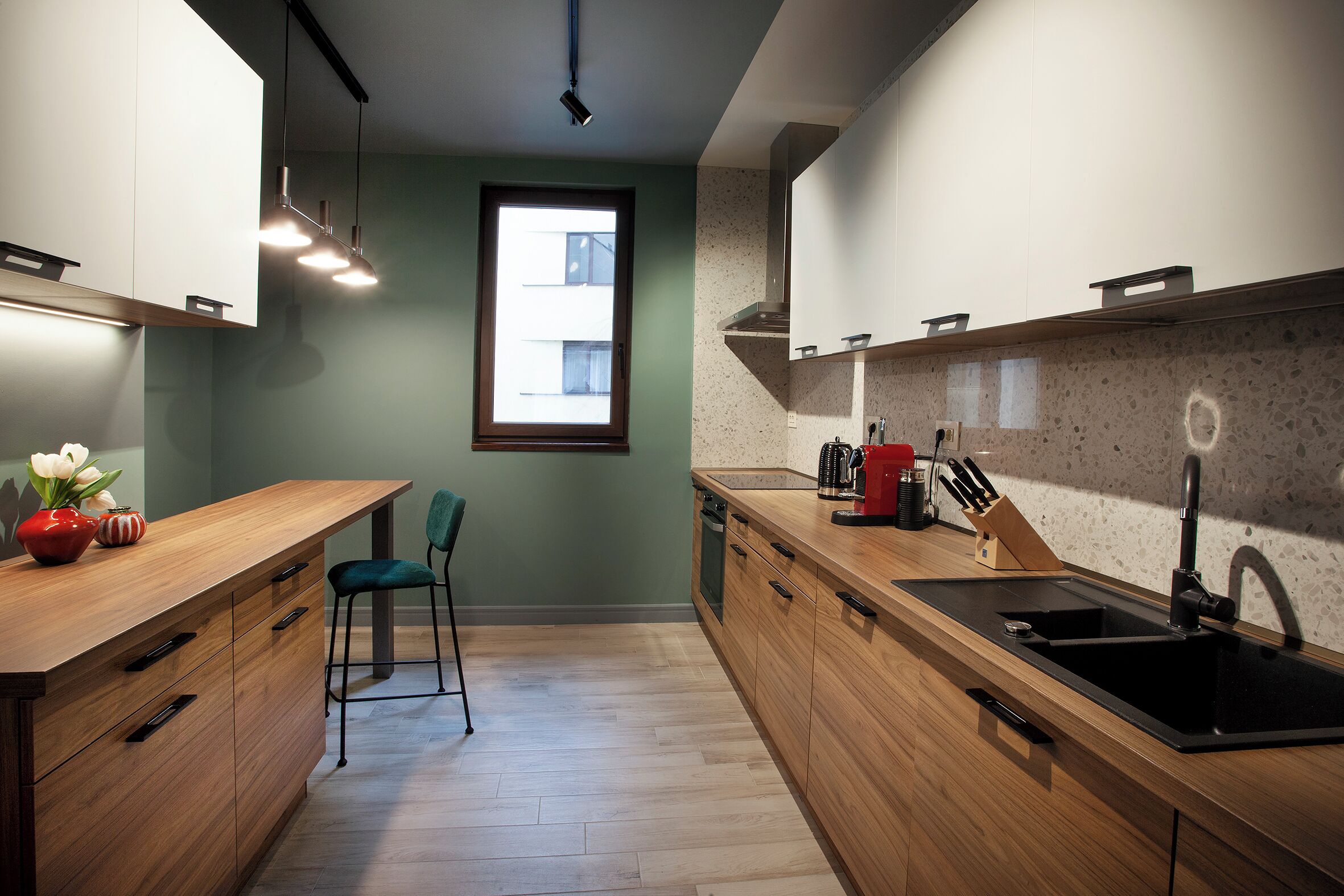 Una cocina moderna con armarios de madera, un lavamanos negro y un ventanal que proporciona luz natural.