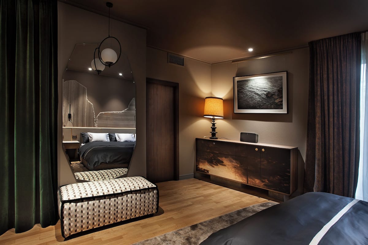 A modern bedroom with a bed, bedside table, lamp, and a painting on the wall.