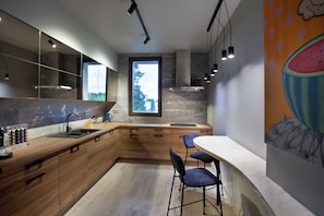A modern kitchen with wooden cabinets, a marble countertop, and a large window. - Room12 (Bucharest)