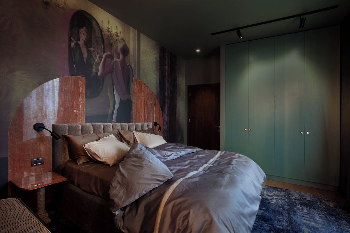 A modern bedroom with a large bed, a headboard, a nightstand, and a wardrobe.
