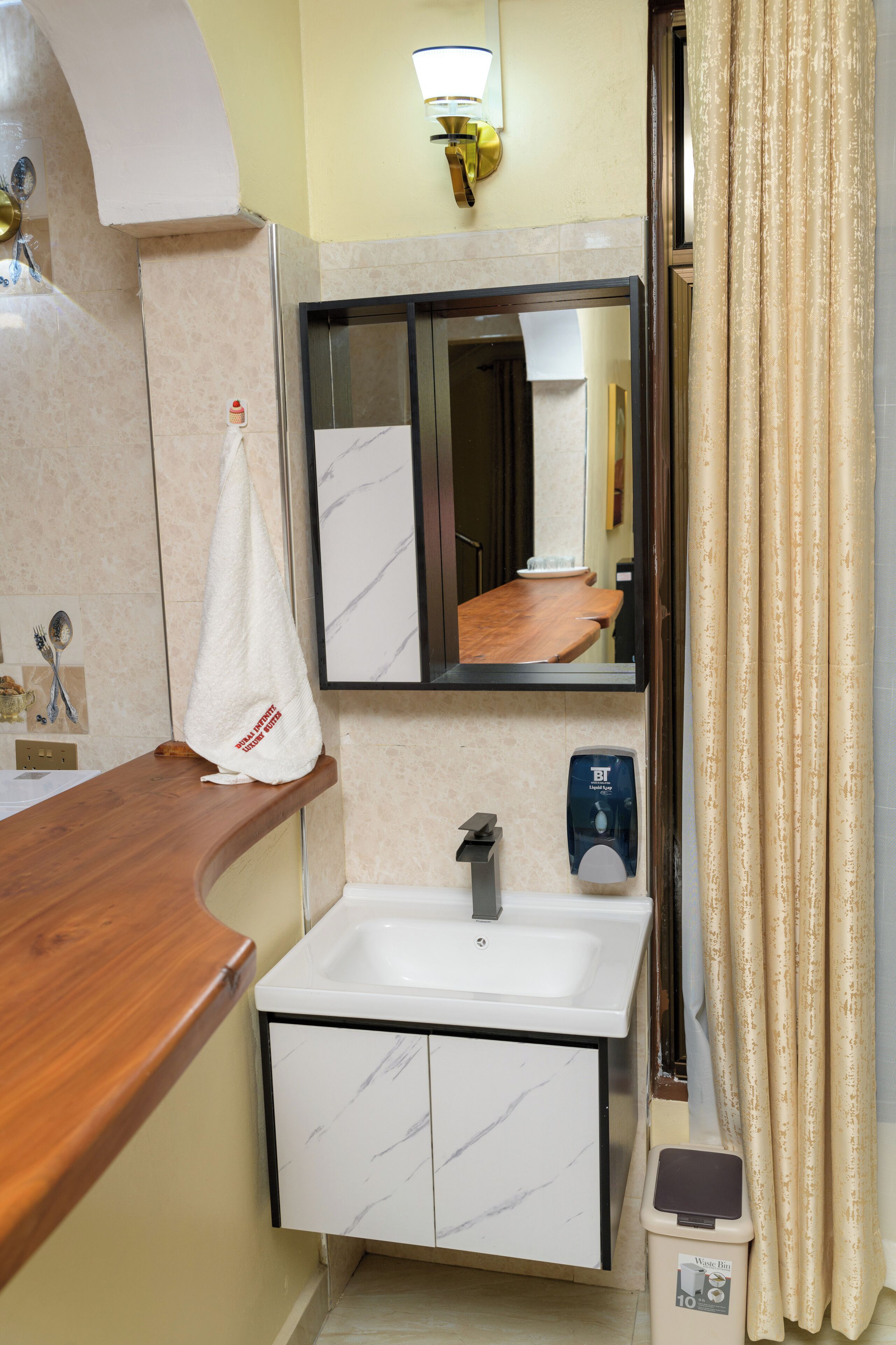 A bathroom with a marble sink, a mirror, a towel hanging on the wall, and a hand dryer.