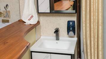 Une salle de bain avec un lavabo en marbre, un miroir, une serviette accrochée au mur et un sèche-mains.
