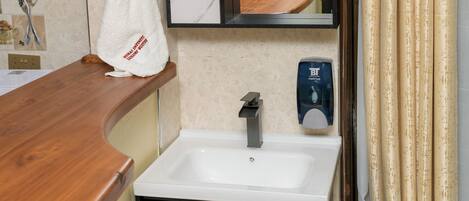 A bathroom with a marble sink, a mirror, a towel hanging on the wall, and a hand dryer.